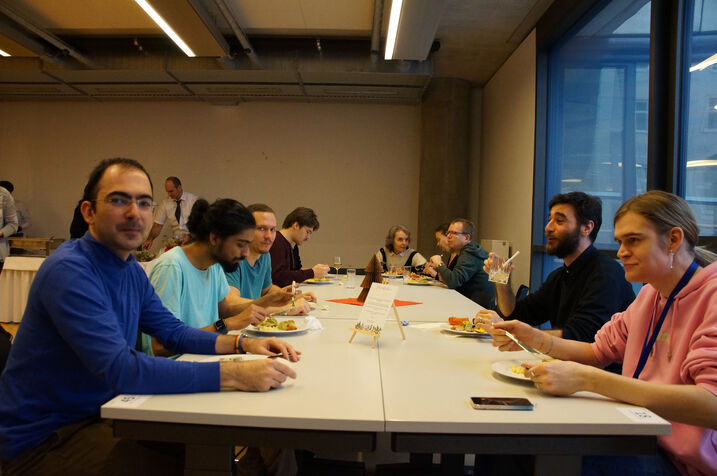 Fakultätsmitglieder sitzen um einen großen Tisch im Seminarraum und essen.