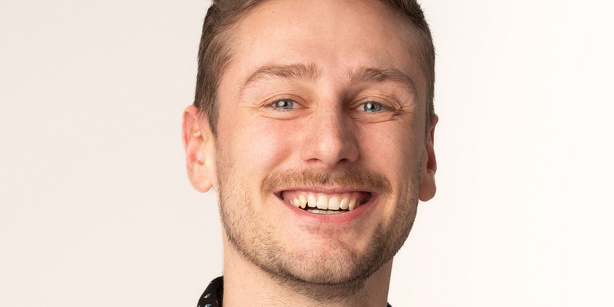Lukas Hinterleitner smiling at the camera against a white background.
